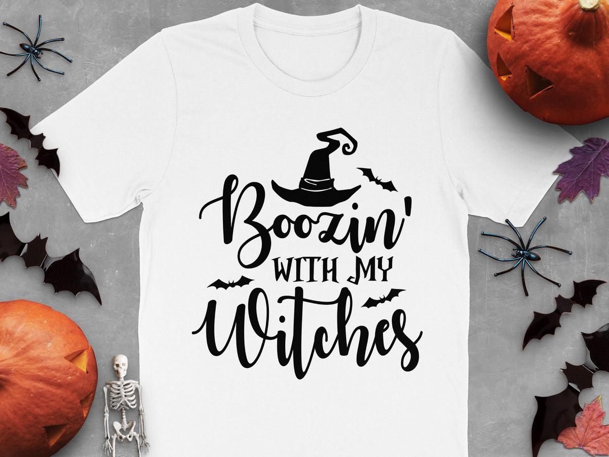 White t-shirt with "Boozin' With My Witches" text and Halloween decorations.